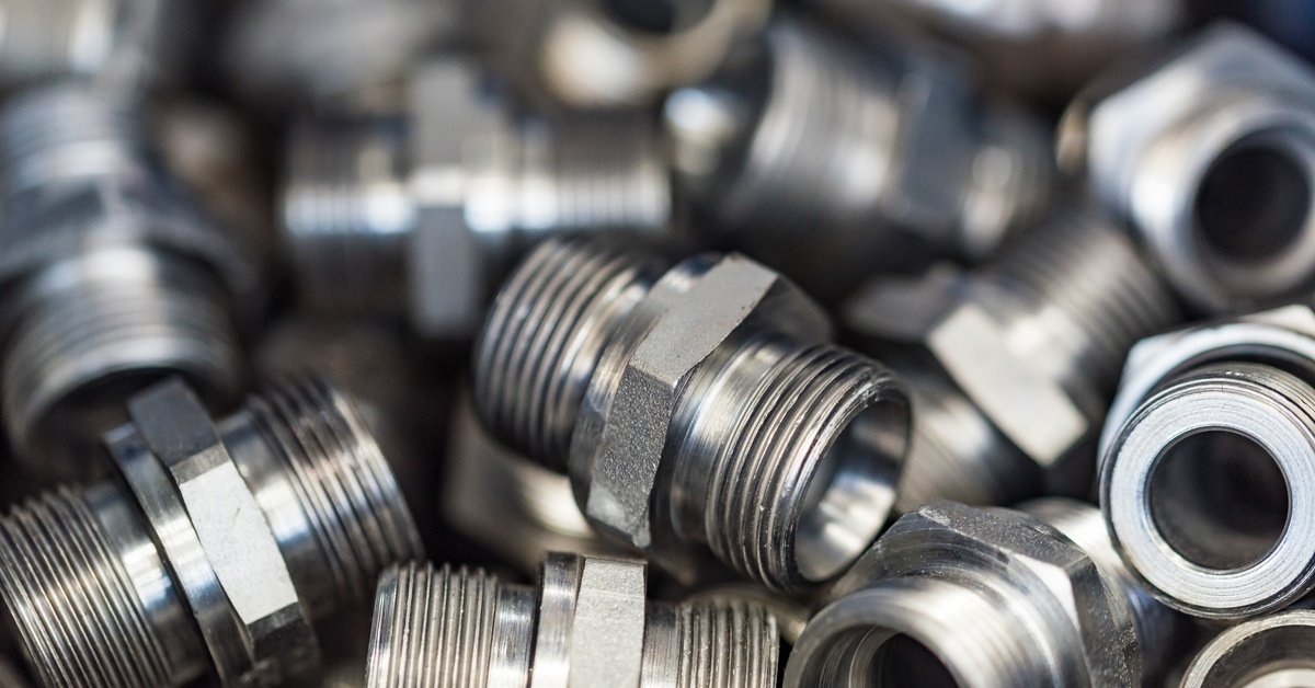 Several metal hydraulic adapters are clear in the foreground, while the rest appear blurry in the background.