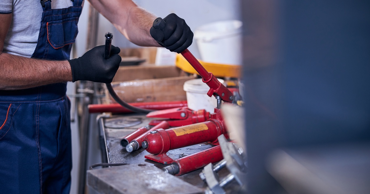 A close-up of a male worker's hand as he's assembling a portable hydraulic tool in the warehouse garage.
