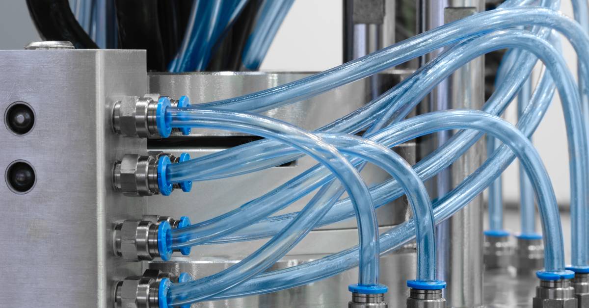 A stainless steel pneumatic system with several light-blue tubes coming out of various connectors around the system.