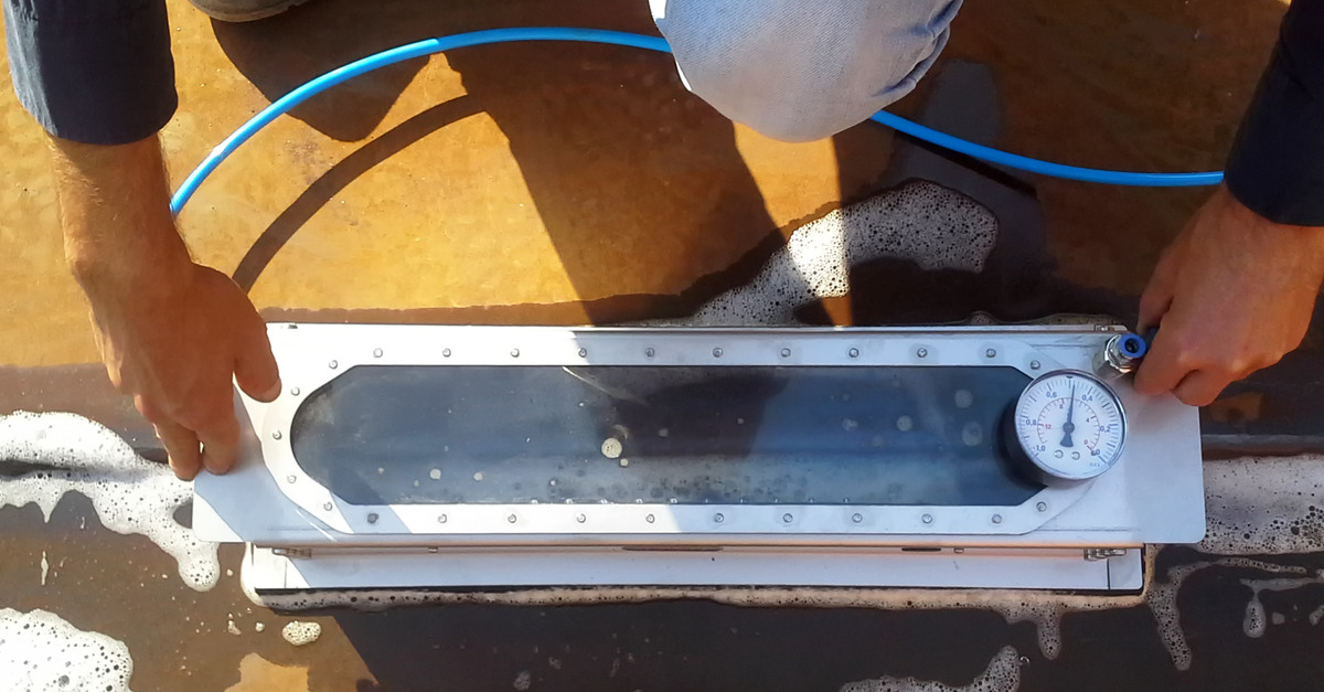 An overhead view of a man's hands as they use a liquid application technique to perform an air leak detection test.